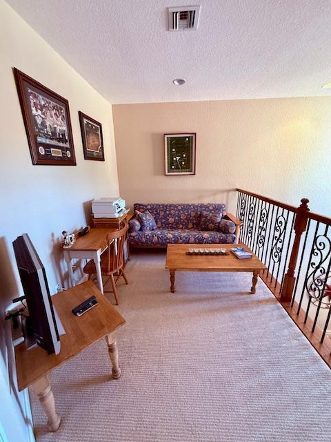 living area with a textured ceiling and carpet