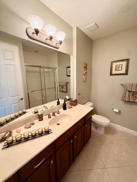 full bathroom with a shower stall, tile patterned floors, vanity, toilet, and a textured ceiling