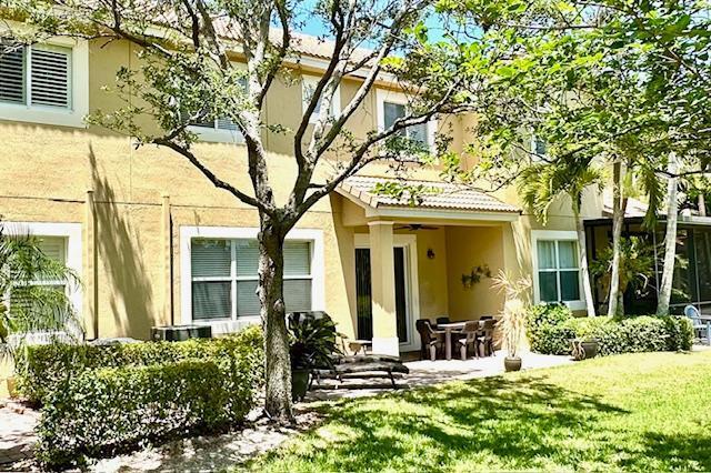 back of house featuring stucco siding, a yard, a patio, and ceiling fan