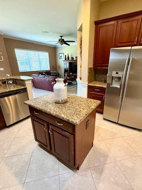 kitchen featuring appliances with stainless steel finishes, ceiling fan, light stone counters, and light tile patterned flooring
