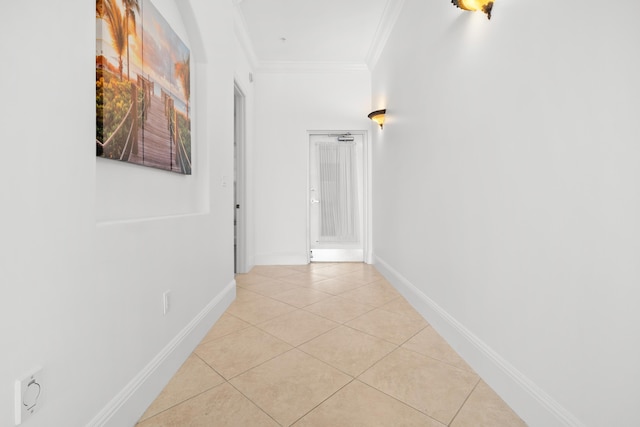 hallway with light tile patterned floors, crown molding, and baseboards