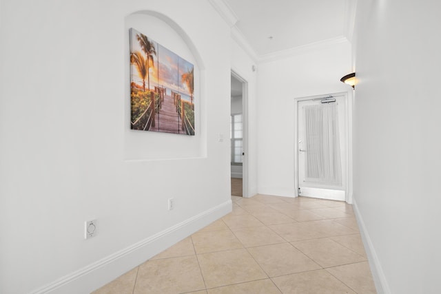 hall featuring crown molding, light tile patterned flooring, and baseboards