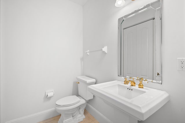 half bathroom with baseboards, toilet, and tile patterned floors