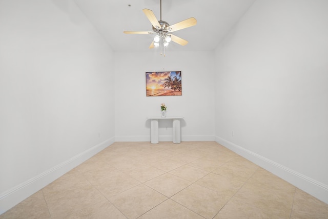 empty room with ceiling fan, light tile patterned floors, vaulted ceiling, and baseboards