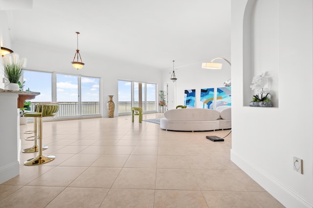 living area with light tile patterned flooring, baseboards, and arched walkways