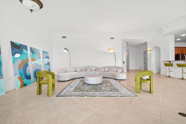 tiled living room with ornamental molding and arched walkways