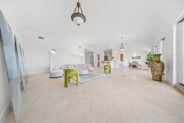 living room with arched walkways, light tile patterned flooring, and ornamental molding