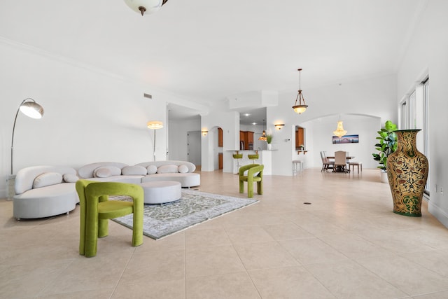 living area featuring arched walkways, ornamental molding, and tile patterned floors