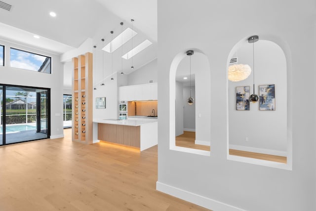 17726 Litten Dr, Boca Raton, FL 33498 - unfurnished living room featuring a towering ceiling, recessed lighting, a skylight, baseboards, and light wood finished floors