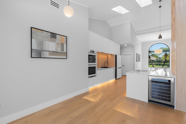 17726 Litten Dr, Boca Raton, FL 33498 - kitchen with wine cooler, light wood-style floors, double oven, a sink, and vaulted ceiling