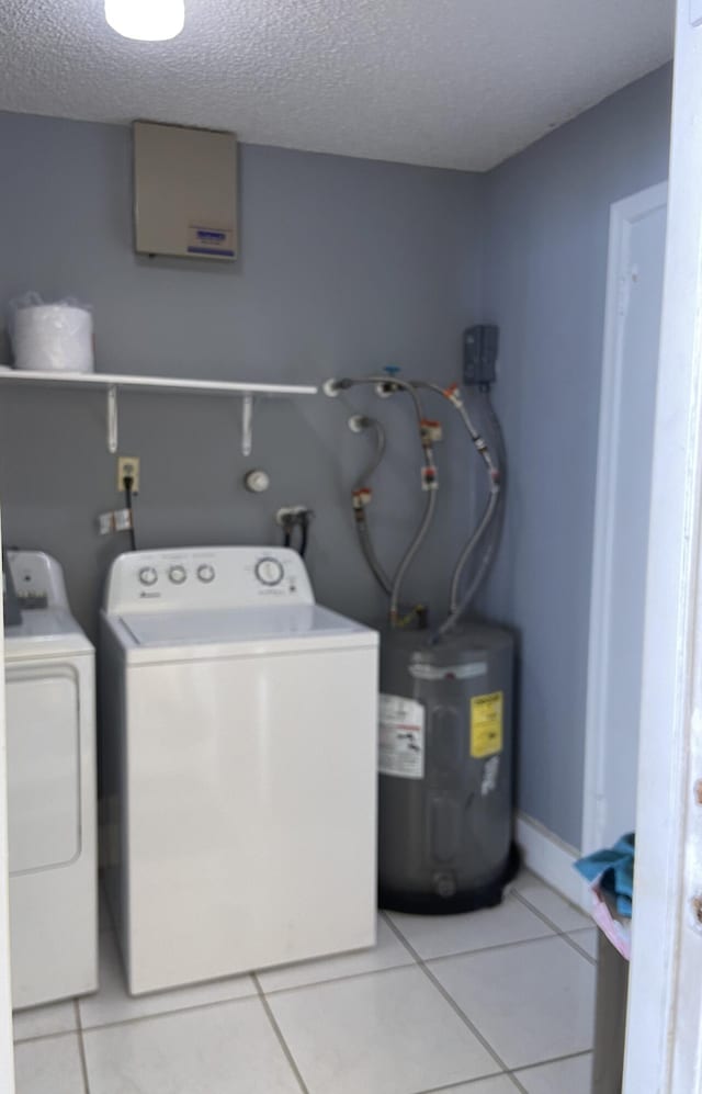 laundry area featuring water heater, washing machine and clothes dryer, a textured ceiling, and light tile patterned floors