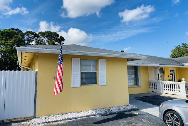 view of property exterior with stucco siding, fence, and roof with shingles