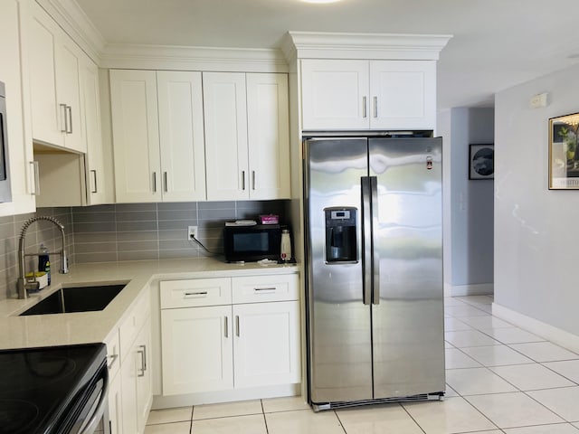 kitchen featuring stainless steel fridge, a sink, black microwave, and backsplash