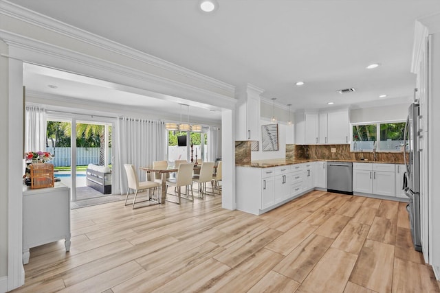 1096 SW 16th St, Boca Raton, FL 33486 - kitchen featuring appliances with stainless steel finishes, white cabinets, plenty of natural light, decorative backsplash, and crown molding