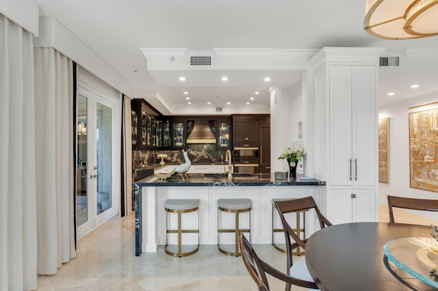 400 S Ocean Blvd Unit R25, Boca Raton, FL 33432 - kitchen featuring decorative backsplash, premium range hood, glass insert cabinets, a breakfast bar, and white cabinetry