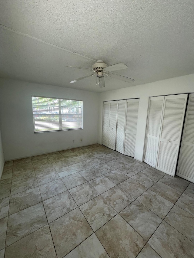 4269 NW 89th Ave Unit 106, Coral Springs, FL 33065 - unfurnished bedroom featuring two closets, a textured ceiling, and a ceiling fan