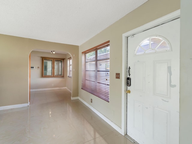 1421 E River Dr, Margate, FL 33063 - entryway featuring arched walkways, a textured ceiling, baseboards, and light tile patterned flooring
