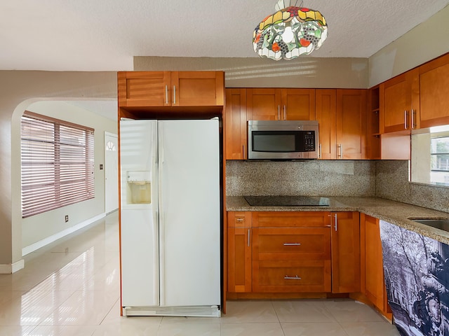 1421 E River Dr, Margate, FL 33063 - kitchen featuring white fridge with ice dispenser, stainless steel microwave, black electric cooktop, light tile patterned floors, and brown cabinets