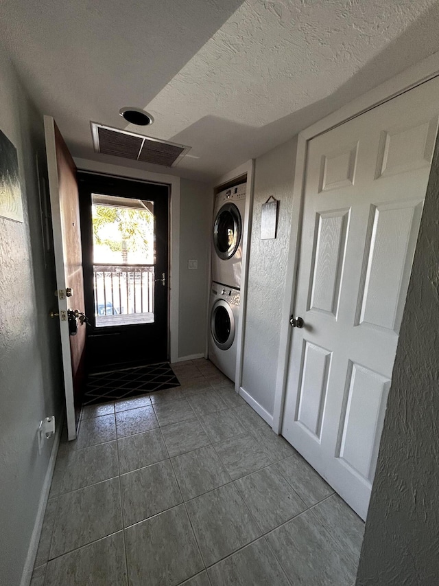 500 N Francisco St Unit 211, Clewiston, FL 33440 - laundry room featuring stacked washer / dryer, baseboards, a textured ceiling, and tile patterned floors