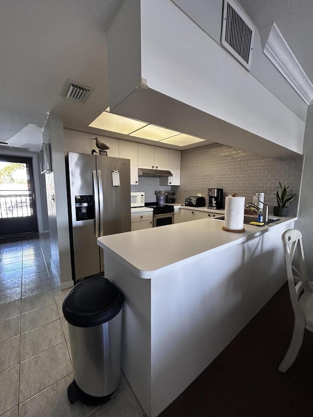 500 N Francisco St Unit 211, Clewiston, FL 33440 - kitchen with stainless steel appliances, a peninsula, light countertops, light tile patterned flooring, and white cabinets