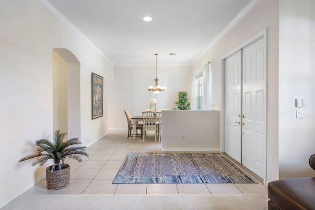 foyer entrance with ornamental molding, arched walkways, a chandelier, light tile patterned floors, and baseboards