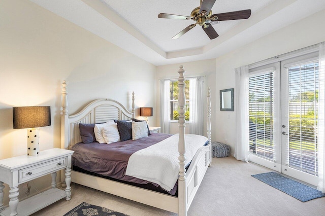 bedroom featuring light carpet, access to outside, french doors, a raised ceiling, and ceiling fan