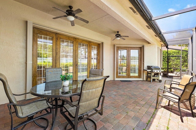 view of patio with french doors, ceiling fan, outdoor dining area, and a lanai