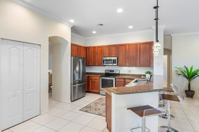 kitchen with appliances with stainless steel finishes, a sink, a peninsula, a breakfast bar, and light tile patterned floors