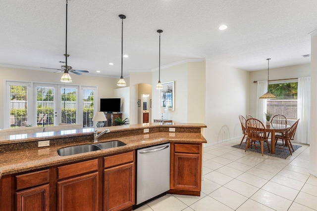 kitchen featuring dishwasher, a sink, brown cabinets, hanging light fixtures, and light tile patterned flooring