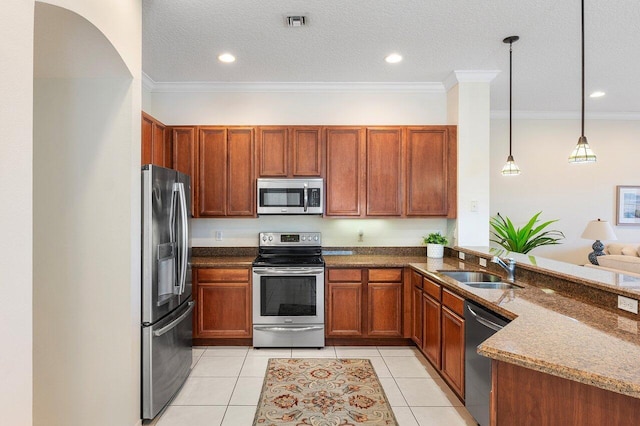 kitchen with appliances with stainless steel finishes, a sink, dark stone countertops, light tile patterned floors, and crown molding