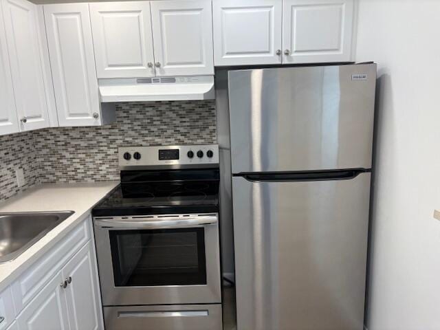 kitchen featuring appliances with stainless steel finishes, under cabinet range hood, white cabinetry, and backsplash