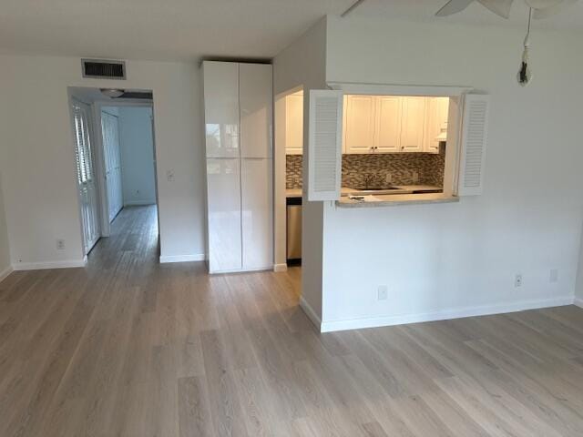 kitchen featuring light wood-style flooring, ceiling fan, tasteful backsplash, and baseboards