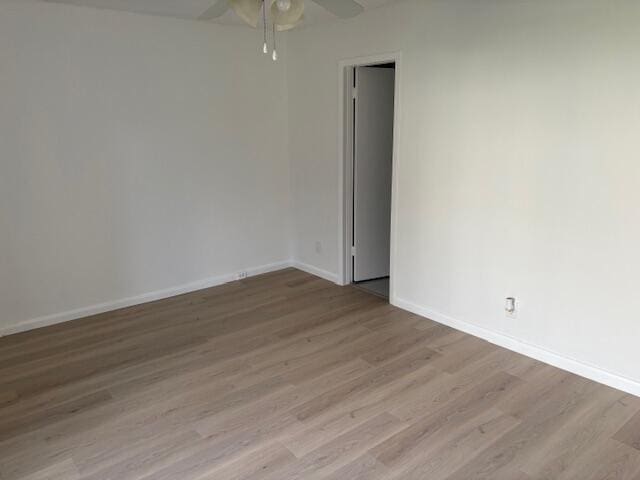empty room with ceiling fan, wood finished floors, and baseboards