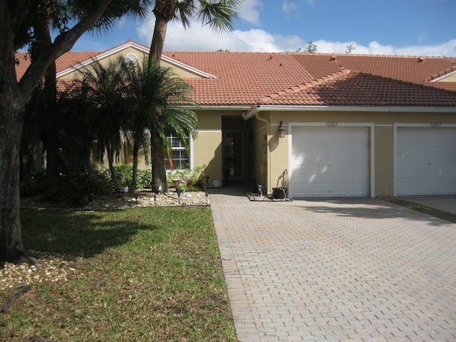 ranch-style house featuring stucco siding, a garage, decorative driveway, and a tiled roof