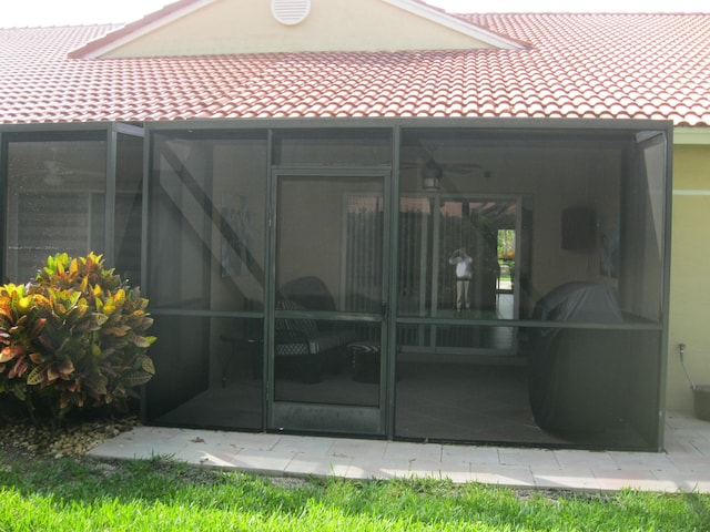 back of house with a tile roof and a sunroom