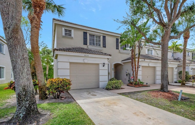 townhome / multi-family property with an attached garage, a tile roof, stucco siding, and driveway