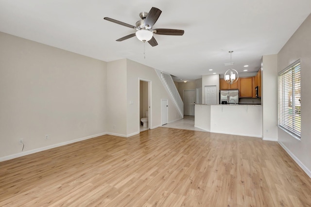 unfurnished living room featuring light wood finished floors, baseboards, a ceiling fan, recessed lighting, and a chandelier