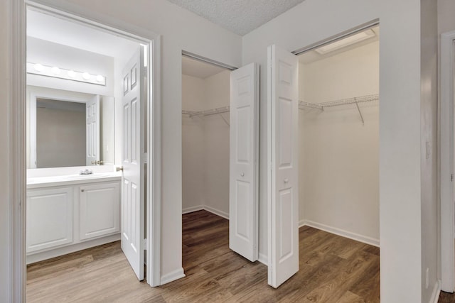 unfurnished bedroom with a sink, light wood-type flooring, a spacious closet, and a closet