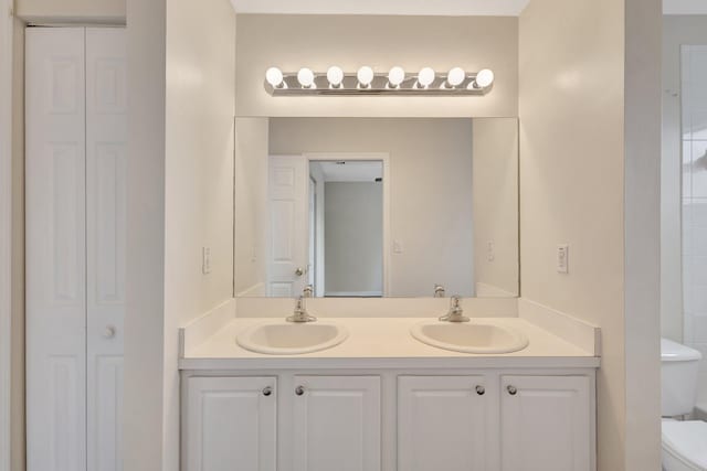 bathroom featuring a closet, toilet, and double vanity