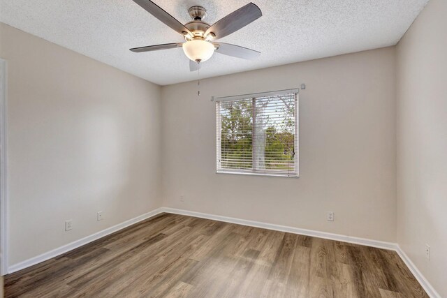 unfurnished room featuring wood finished floors, a ceiling fan, baseboards, and a textured ceiling