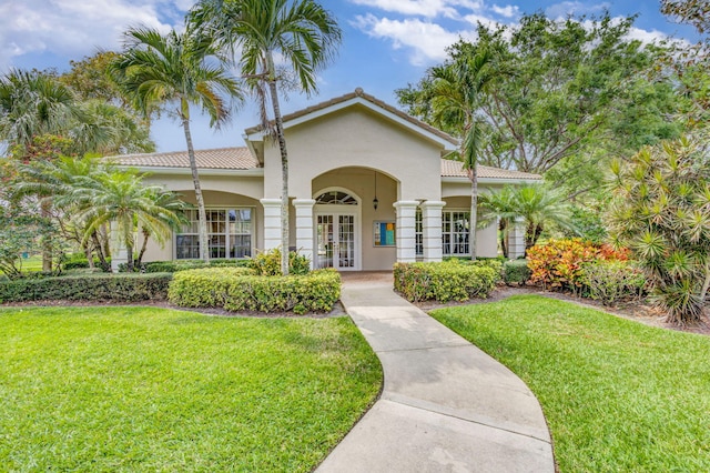 mediterranean / spanish-style house featuring french doors, stucco siding, a tile roof, and a front lawn