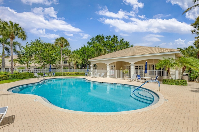 community pool with fence and a patio