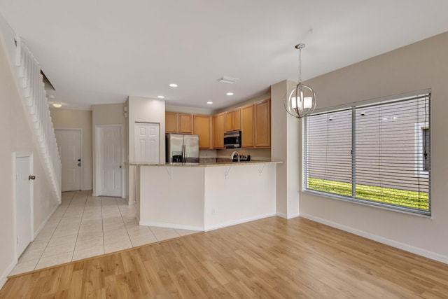 kitchen featuring stainless steel appliances, baseboards, light wood-style floors, a peninsula, and a chandelier