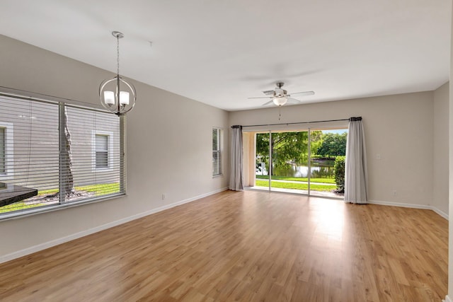 unfurnished room featuring light wood-style floors, baseboards, a ceiling fan, and a chandelier