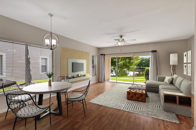 dining space featuring ceiling fan, wood finished floors, baseboards, and a chandelier