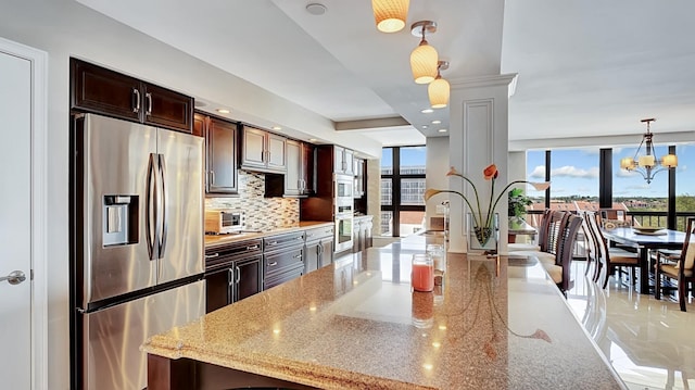 4740 S Ocean Blvd Unit 710, Highland Beach, FL 33487 - kitchen featuring stainless steel appliances, decorative backsplash, dark brown cabinetry, decorative light fixtures, and light stone counters