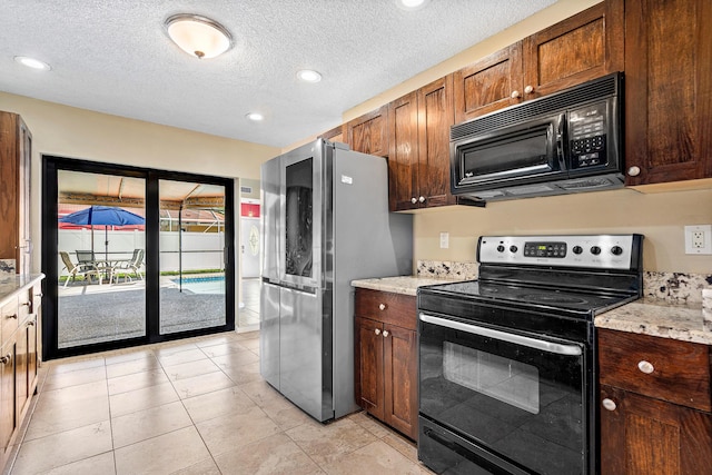 21212 Escondido Way, Boca Raton, FL 33433 - kitchen with black microwave, range with electric cooktop, freestanding refrigerator, a textured ceiling, and light tile patterned flooring