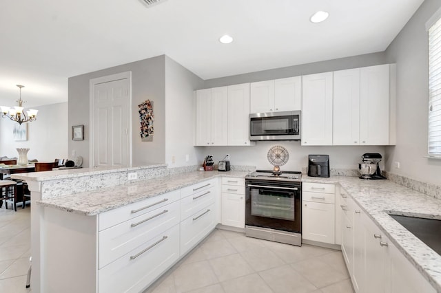 609 Amador Ln Unit 4, West Palm Beach, FL 33401 - kitchen featuring black electric range, stainless steel microwave, light tile patterned flooring, a peninsula, and white cabinets