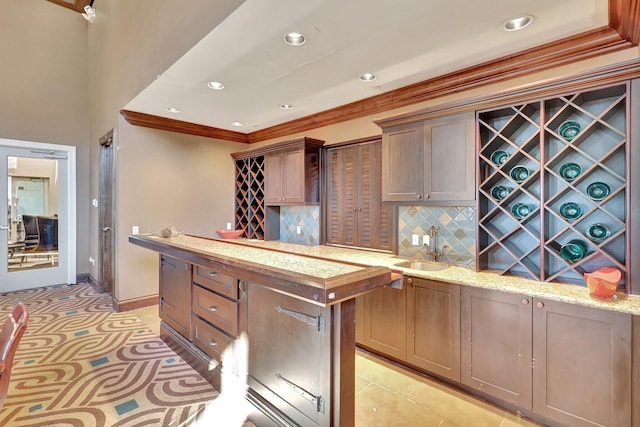 609 Amador Ln Unit 4, West Palm Beach, FL 33401 - kitchen featuring a sink, crown molding, decorative backsplash, a kitchen island, and light stone counters