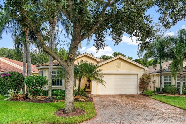 view of front facade featuring a garage, stucco siding, decorative driveway, and a front yard